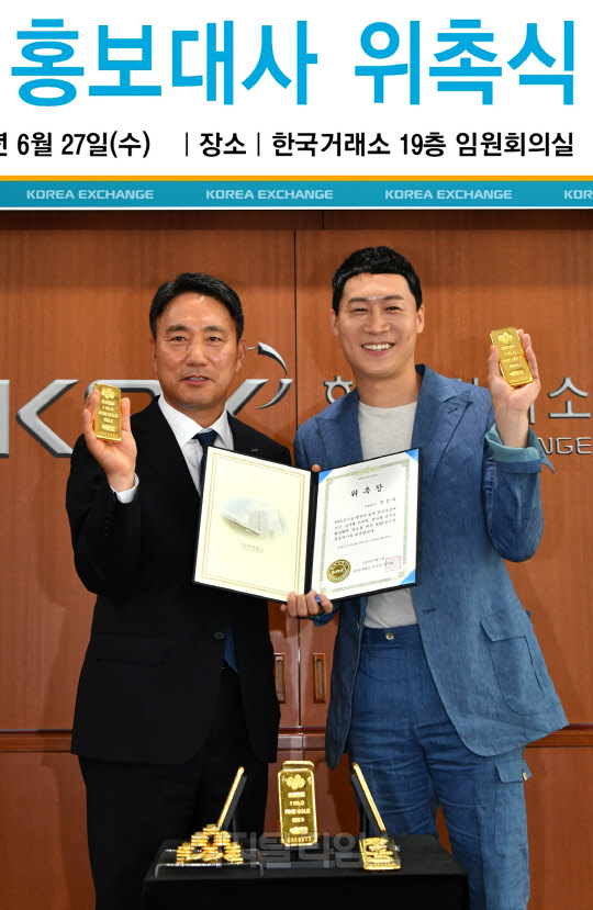 한국거래소는 27일 서울사옥에서 KRX금시장의 브랜드명을 'K금'으로 정하고 영화배우 진선규를 홍보대사로 위촉했다. 위촉장 수여 후 정창희 거래소 파생상품시장본부장(왼쪽)과 진선규 KRX금시장 홍보대사가 기념촬영 하는 모습./사진제공=한국거래소